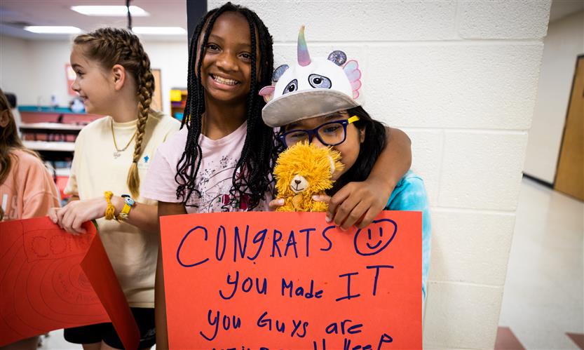 Students hold up signs to encourage graduating seniors